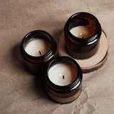 Sample ad, square: three amber jar candles on brown paper.